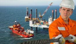 Plataforma de petróleo e um navio de apoio offshore e um homem de uniforme laranja segurando um cabo de aço