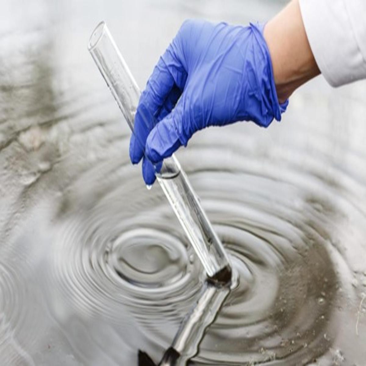 Coleta de amostra de água com tubo de ensaio por pesquisador com luva azul 🏷️ Título da imagem: Amostragem de á