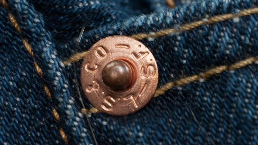 Os pequenos botões do jeans são mais que detalhe: uma solução engenhosa que garantiu resistência e virou símbolo da moda em quase 150 anos.