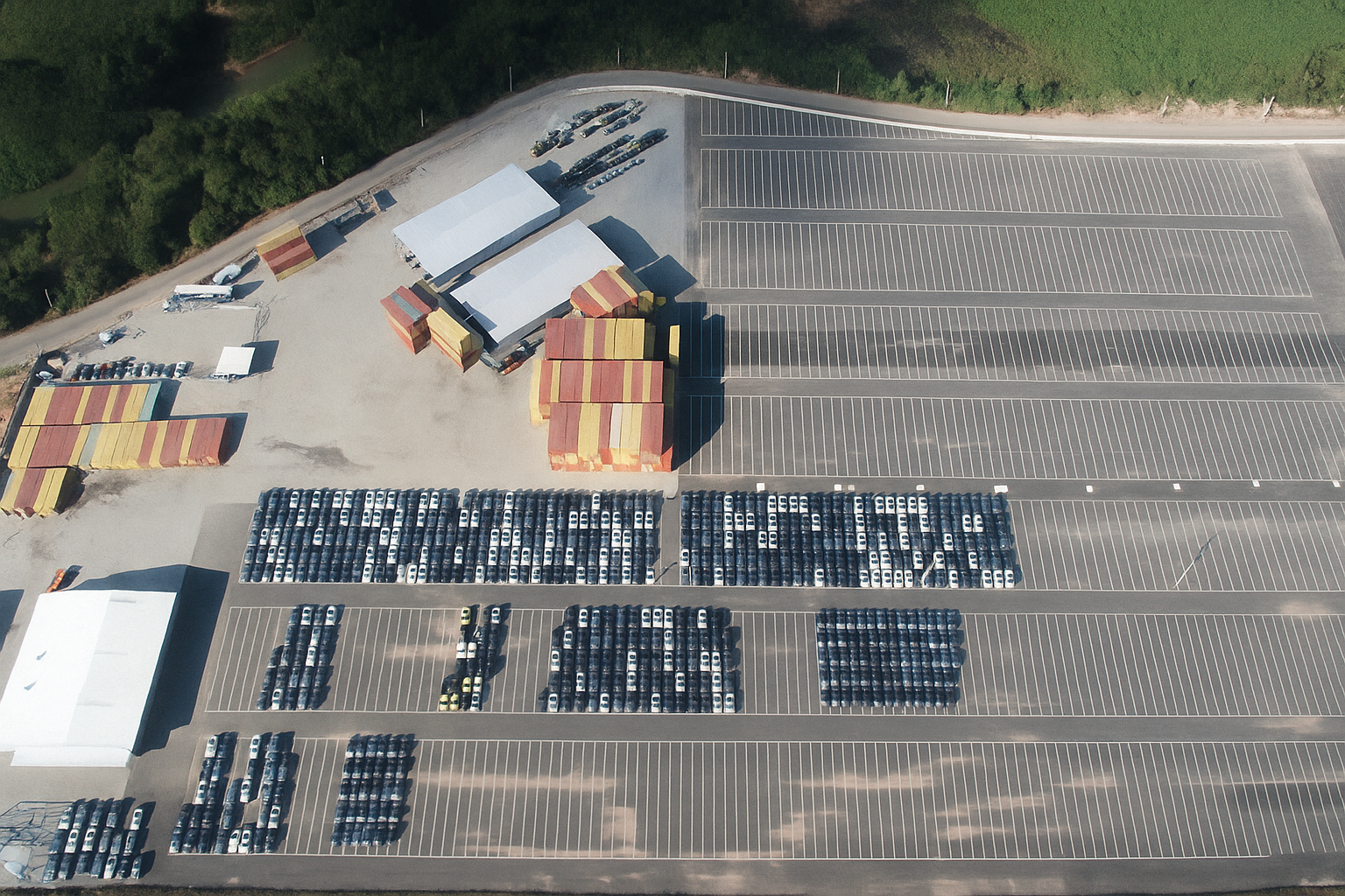 Vista aérea de centro logístico com pátio de veículos e galpões em área industrial