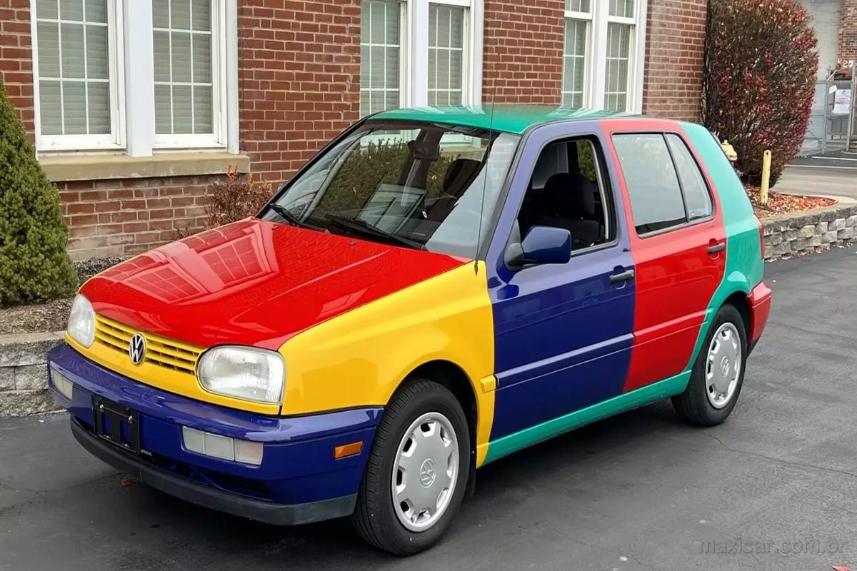 Volkswagen Golf Harlequin multicolorido estacionado em frente a prédio de tijolos