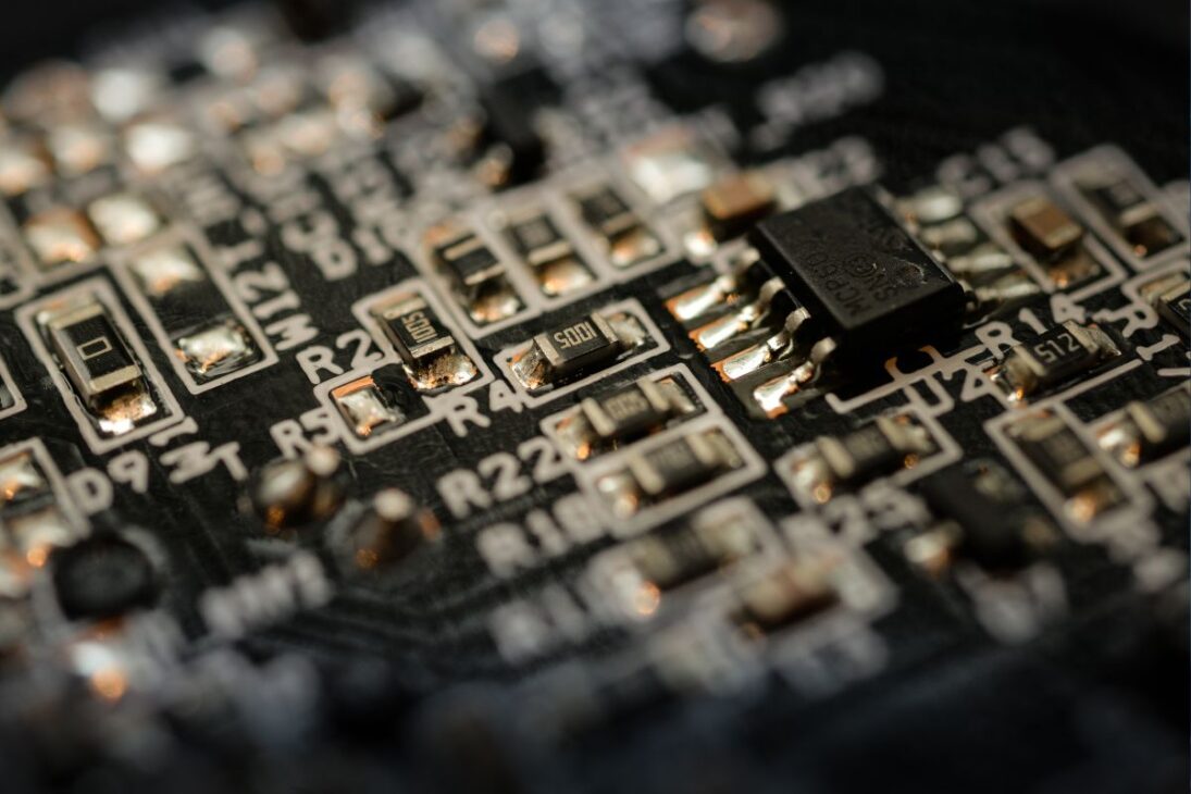 Close-up de placa eletrônica com microchip e componentes SMD soldados, ilustrando a miniaturização e precisão da tecnologia digital moderna.