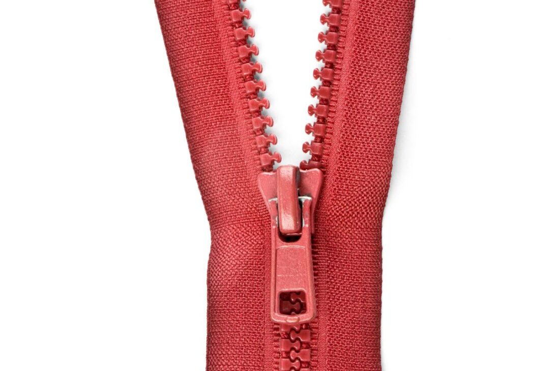 Zíper de plástico vermelho com dentes grandes e visíveis, com o puxador na parte inferior central, sobre um fundo branco puro.
