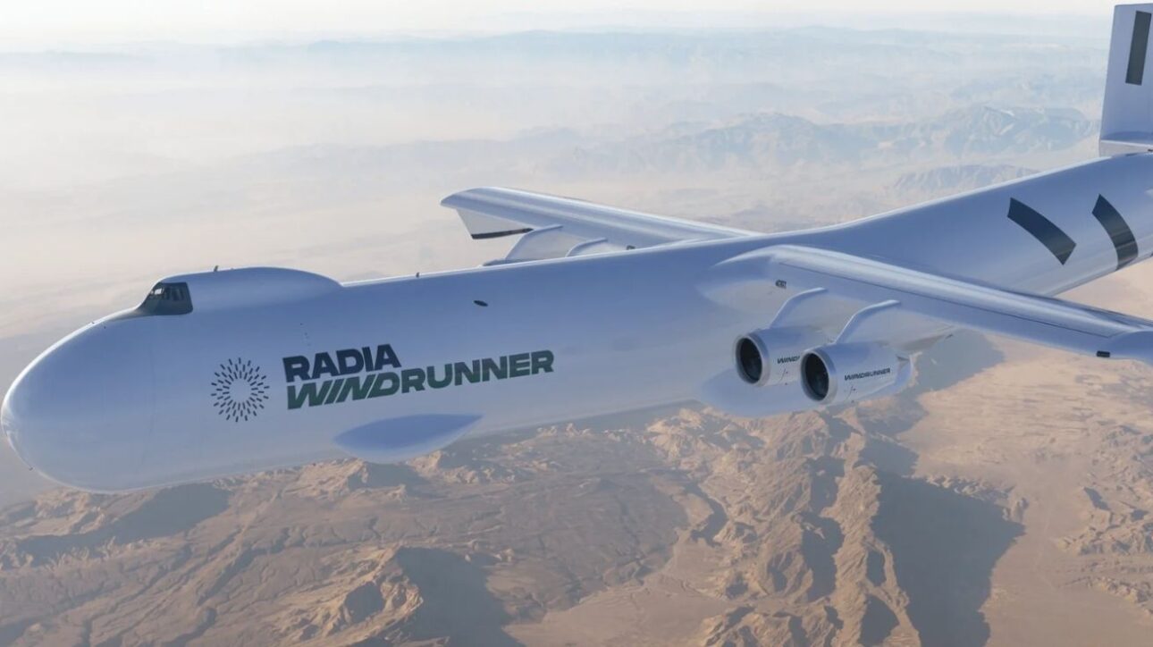Avião WindRunner da Radia Corporation voando sobre região montanhosa e desértica, destacando seu design futurista e motores de alta capacidade