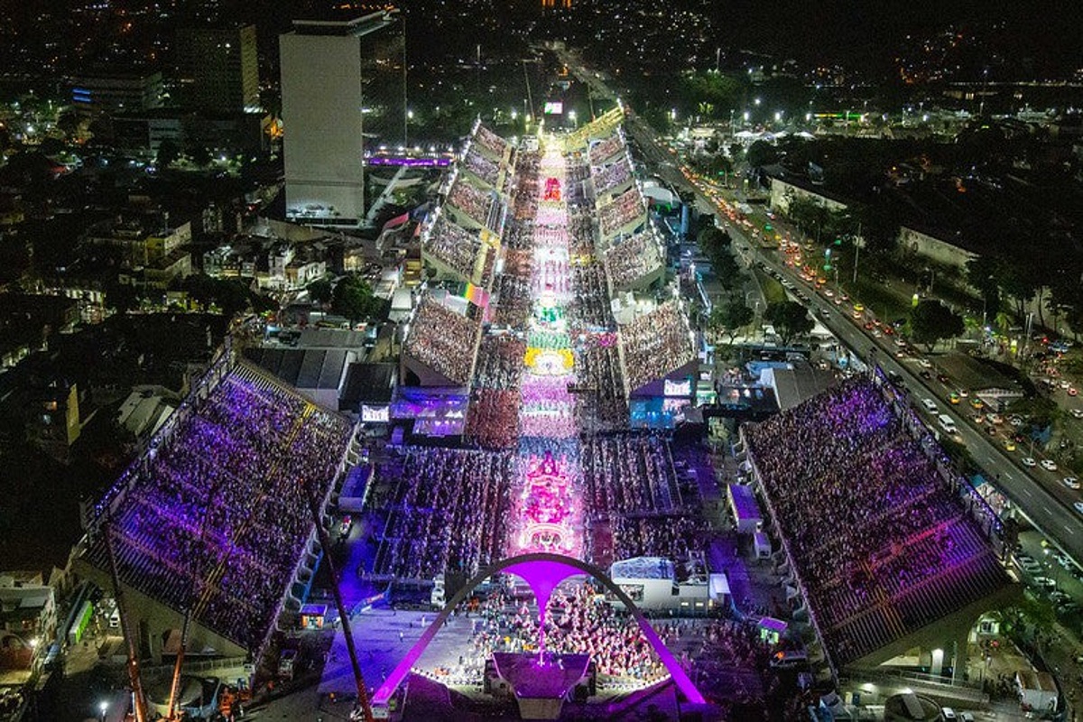 Desfile de escola de samba iluminado no Sambódromo do Rio de Janeiro visto de cima durante o carnaval à noite.