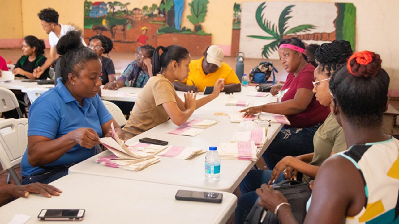 Distribuição de cheques “cash grant” na Guiana reforça transferência de renda com cortes de impostos e auxílio social. (Imagem: Guyana Chronicle)