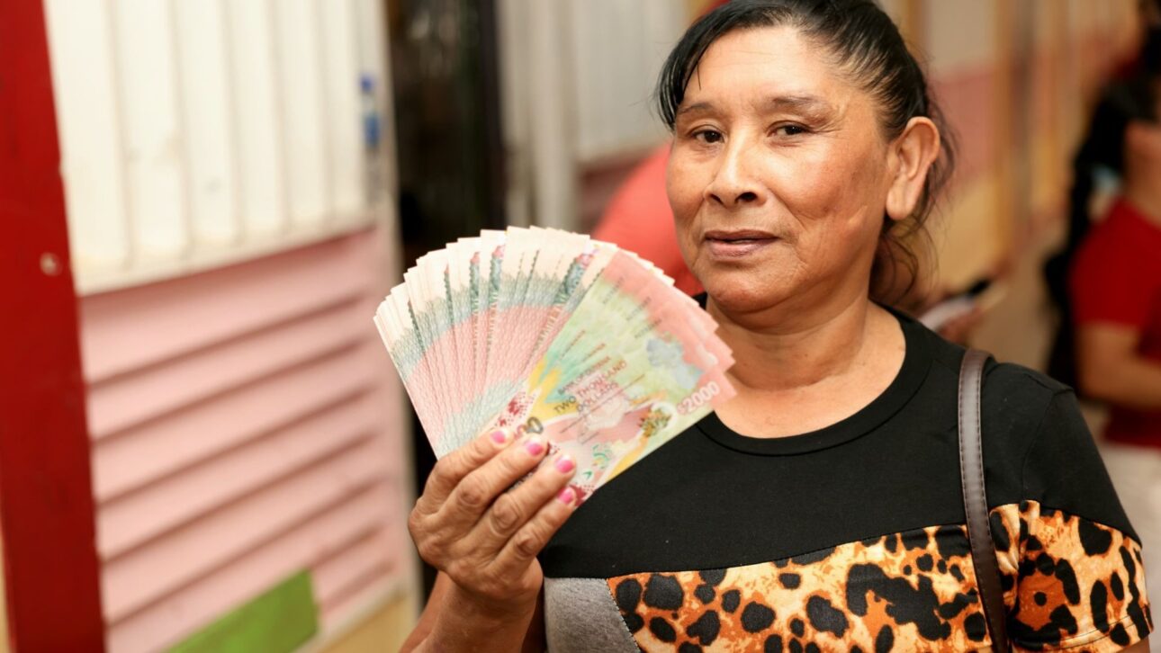 Beneficiária segura benefício em espécie e evidencia o impacto direto dos cheques “cash grant” em R$ para a população da Guiana. (Imagem: Guyana Standard)