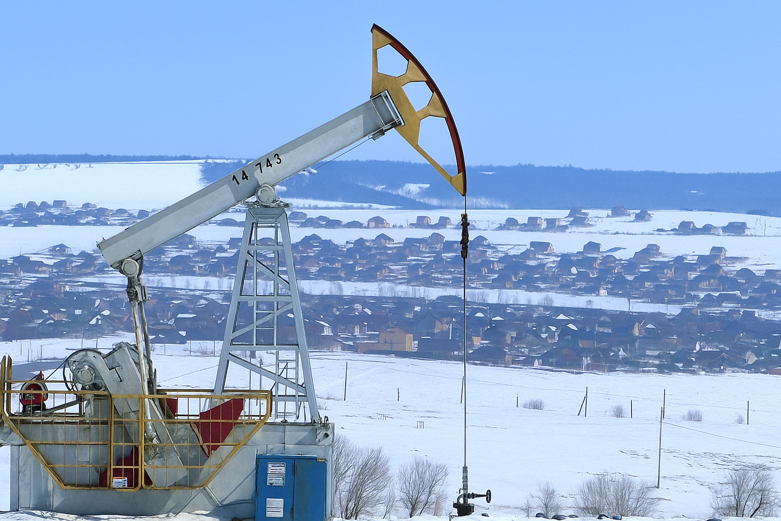 Bomba de extração de petróleo em funcionamento ao meio-dia em uma região nevada.