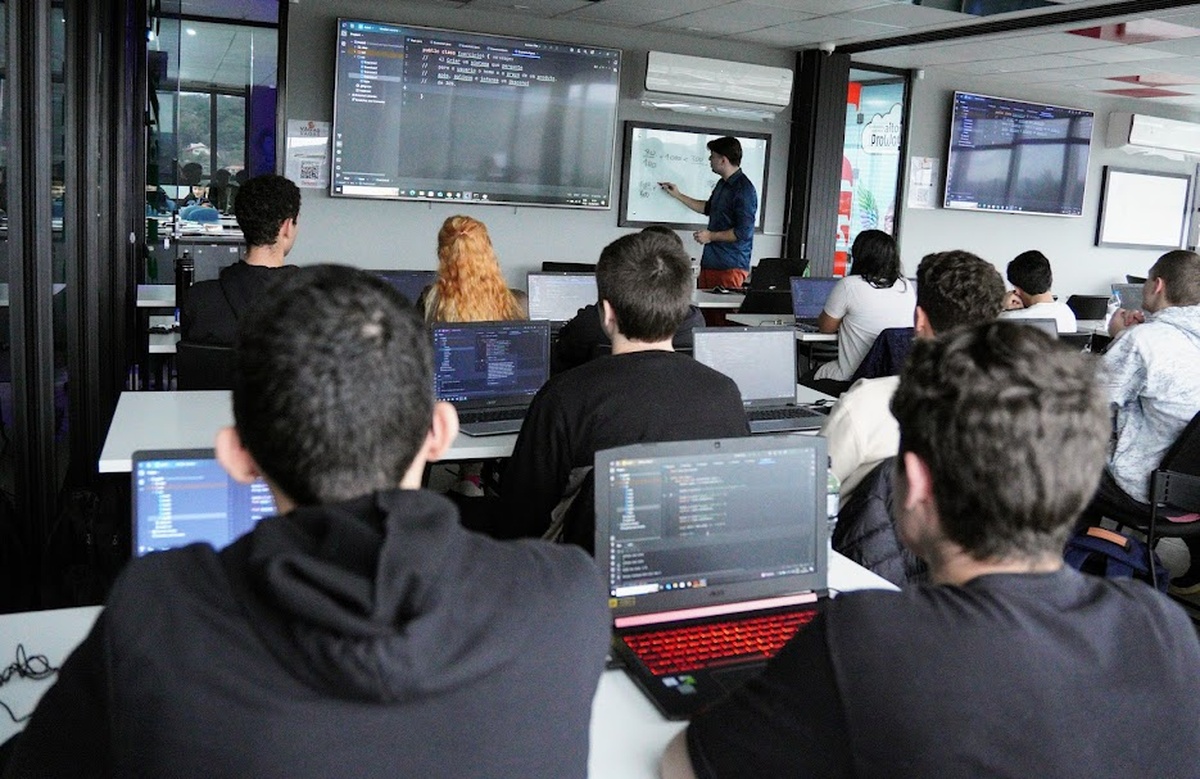 Alunos em aula prática de programação com notebooks na Proway