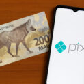 Nota de R$ 200 com lobo-guará ao lado de celular exibindo o aplicativo Pix, simbolizando a queda do dinheiro físico no Brasil.