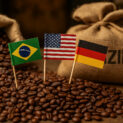 Sacos de café brasileiro com grãos torrados e bandeiras do Brasil, Estados Unidos e Alemanha representando exportações e comércio internacional.