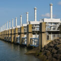 Barragem moderna de energia maremotriz com colunas metálicas e comportas alinhadas sobre o oceano