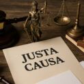 Documento com título “Justa Causa” ao lado de símbolos jurídicos como martelo, balança da justiça e estátua de deusa, representando decisão trabalhista.