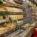 Corredor de supermercado com laticínios e queijos, simbolizando exportações de alimentos do Brasil.