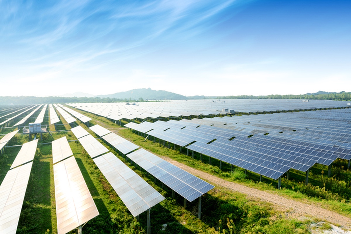 Fazenda solar com centenas de painéis fotovoltaicos sob céu azul claro