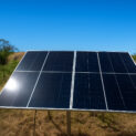 Painel solar instalado em área rural com céu limpo e ensolarado.