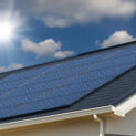 Painéis solares em telhado com céu parcialmente nublado.