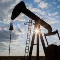 Bomba de extração de petróleo em operação com céu parcialmente nublado ao fundo.