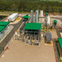 Vista aérea de uma planta industrial com telhados verdes iluminada pela luz do meio-dia.