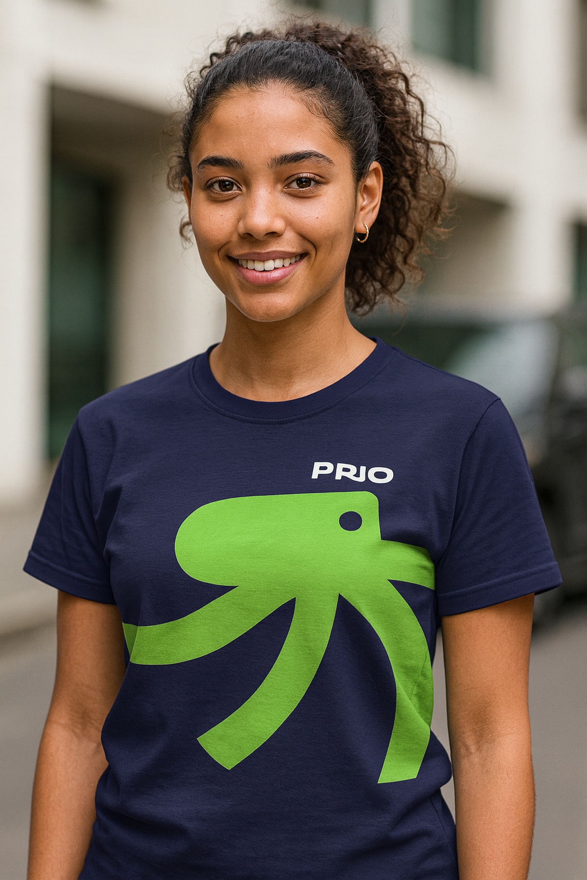 Jovem com camisa da PRIO e logo do polvo verde, simbolizando o Programa de Estágio PRIO 2026 no Rio de Janeiro.