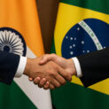 Aperto de mãos diante das bandeiras do Brasil e da Índia simbolizando a ampliação do acordo comercial entre os dois países em 2025.