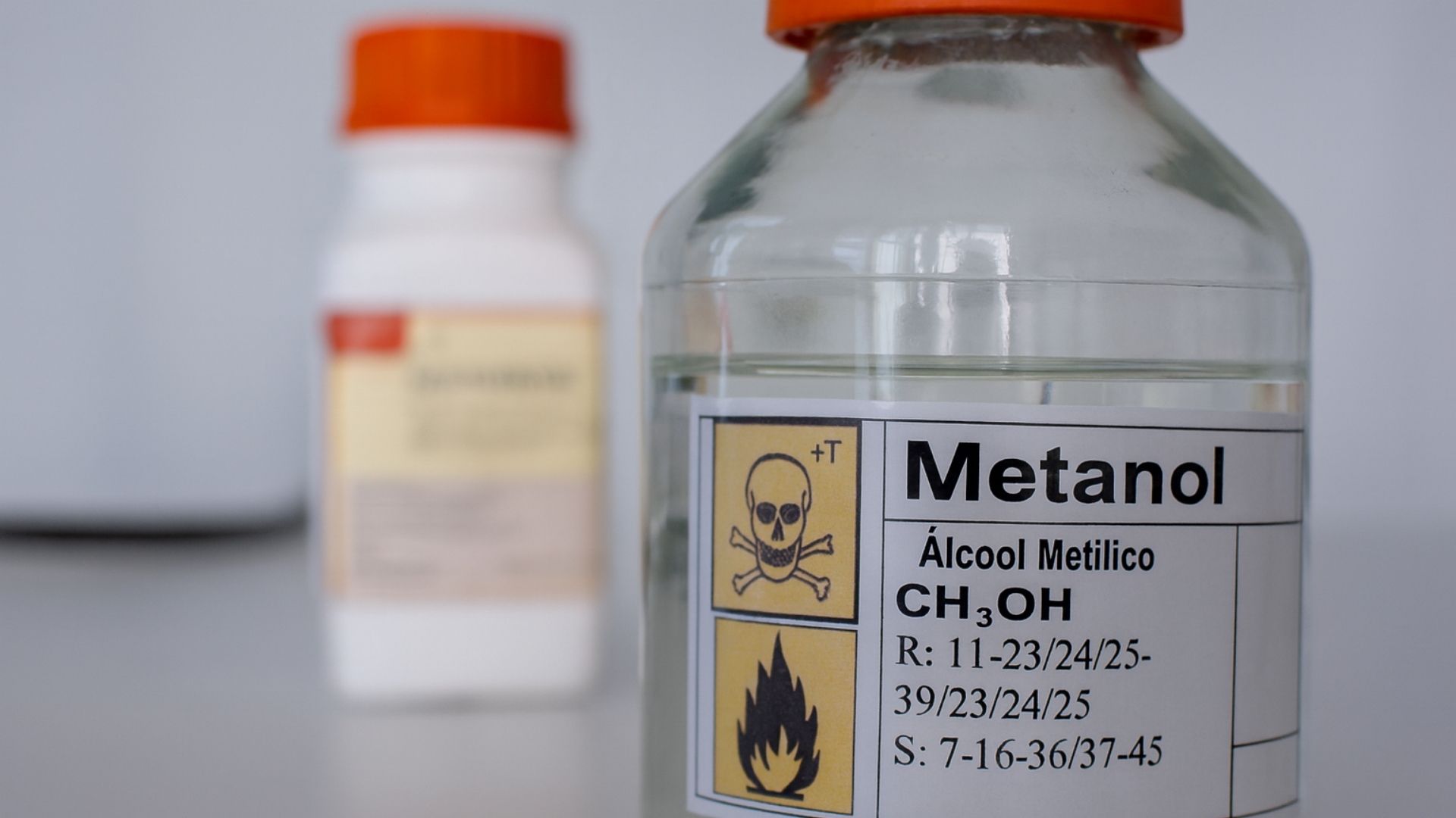 Imagem realista de um frasco transparente com rótulo de metanol e símbolos de perigo químico, representando o alerta emitido pela Anvisa em boletim extra do Diário Oficial da União sobre a autorização emergencial de fabricação de álcool etílico absoluto injetável para tratamento de intoxicação por metanol.