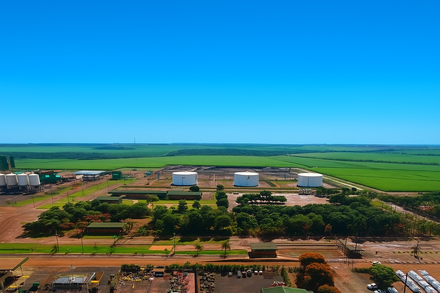 Vista aérea de um moderno parque eólico em meio a campos verdes sob um céu limpo e azul.
