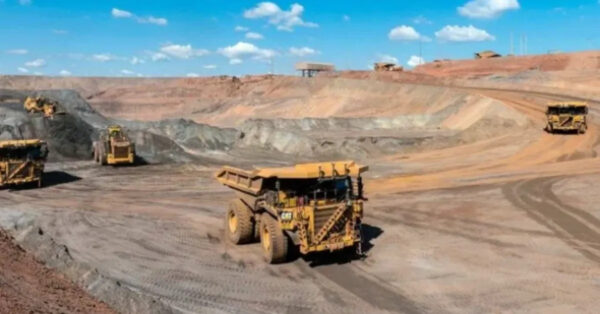 Caminhões de mineração transportando minério em grande mina a céu aberto nos Estados Unidos, representando a expansão da indústria de terras raras.