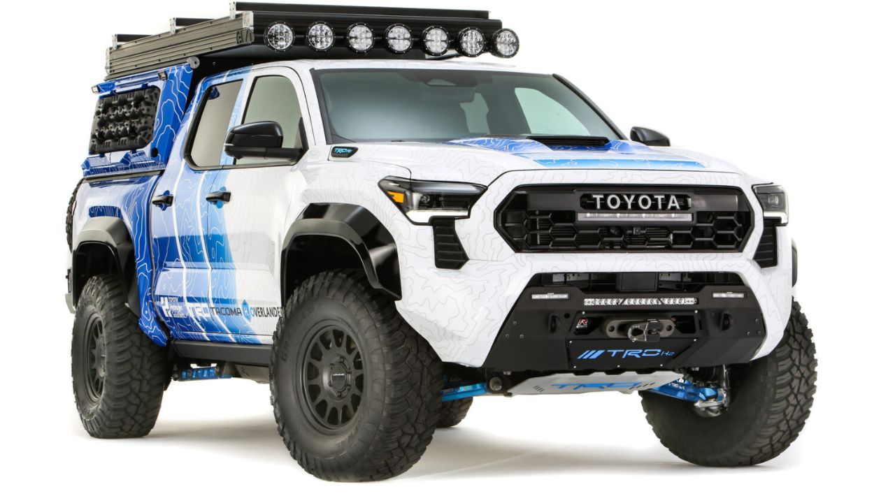 Toyota Tacoma H2Overlander personalizada para expedições off-road, com visual robusto, pneus grandes, suspensão elevada, barra de LED no teto e grafismo topográfico azul e branco.