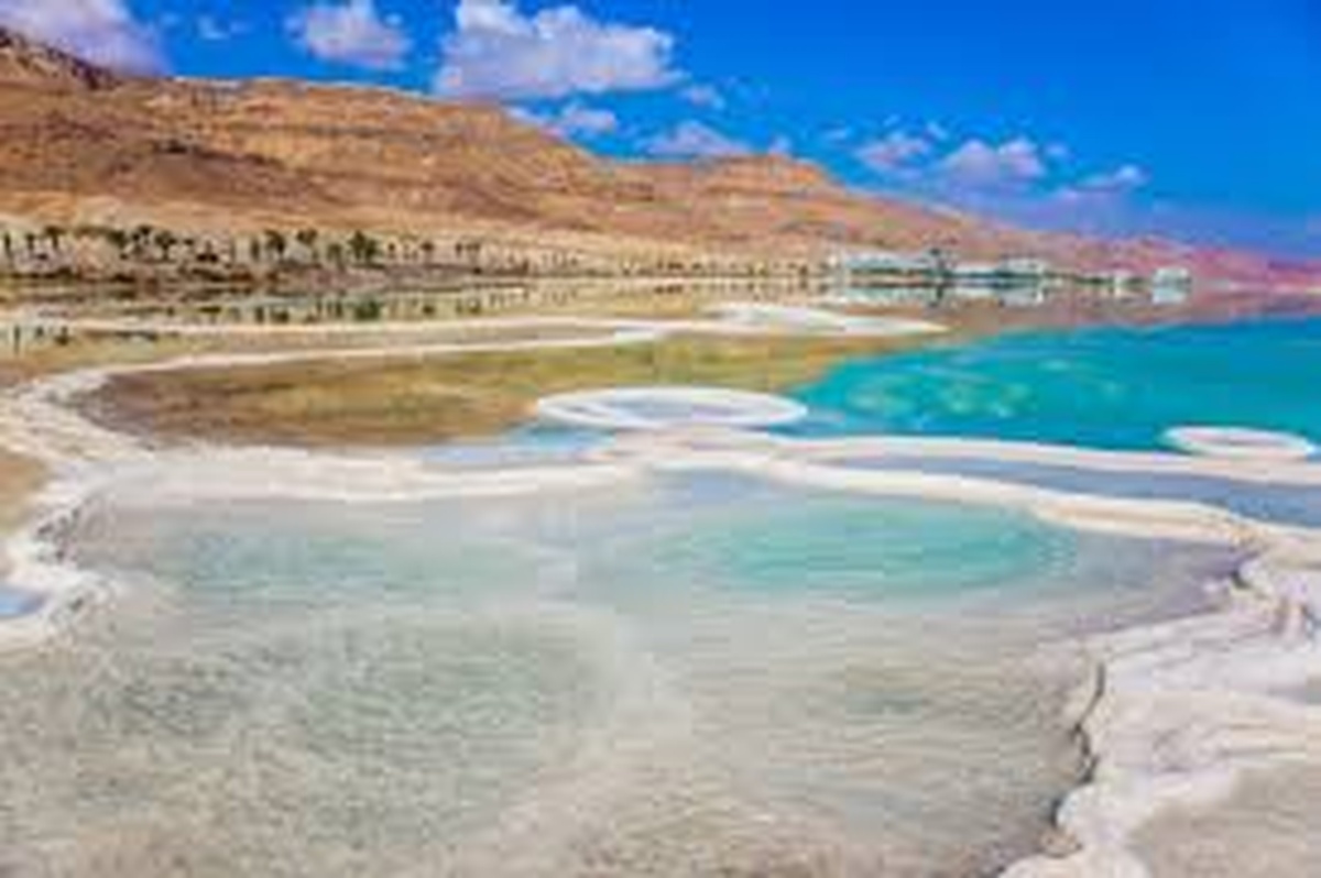 Vista panorâmica do Mar Morto com águas azul-turquesa e margens esbranquiçadas formadas pela alta salinidade