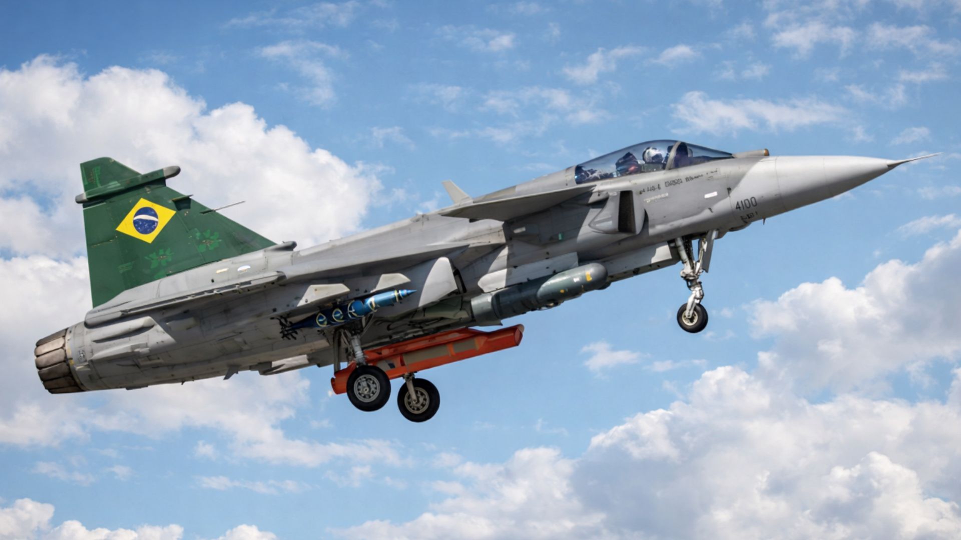 Caça F-39 Gripen da Força Aérea Brasileira em voo com trem de pouso aberto contra céu azul com nuvens