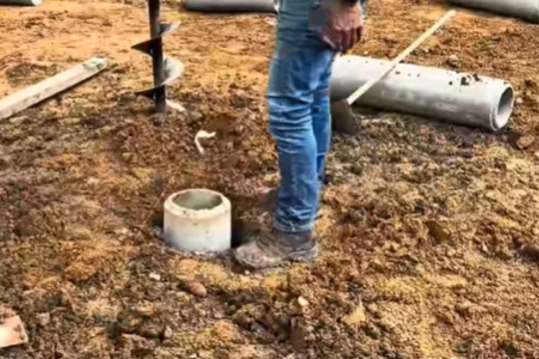 Carpinteiro usa manilhas de concreto e brita compactada na casa de madeira com pilares tipo pilotis e mostra fundação rápida.