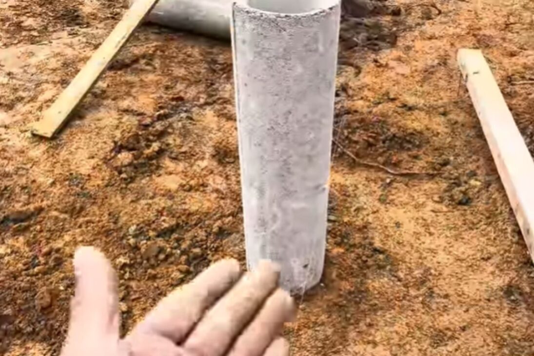 Carpinteiro usa manilhas de concreto e brita compactada na casa de madeira com pilares tipo pilotis e mostra fundação rápida.