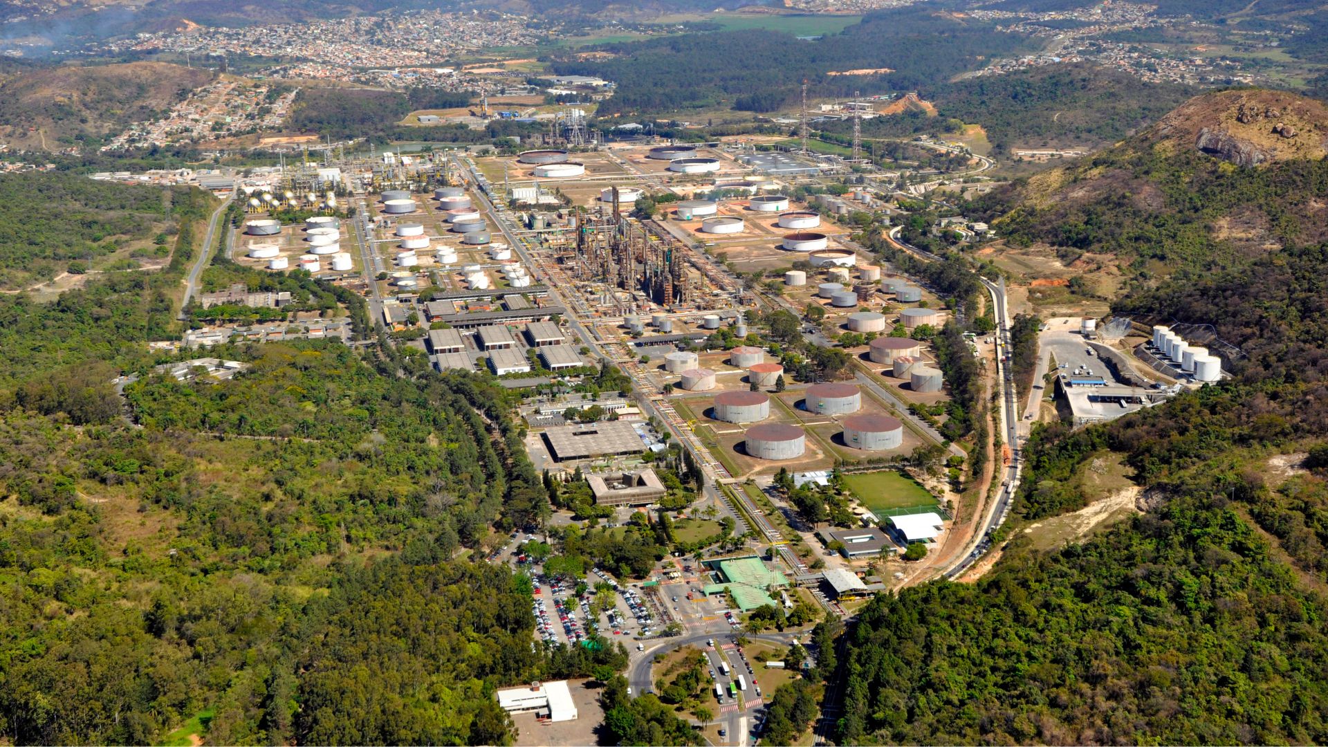 Refinaria Regap da Petrobras em Betim, Minas Gerais, vista aérea com tanques de armazenamento, unidades industriais e área cercada por vegetação