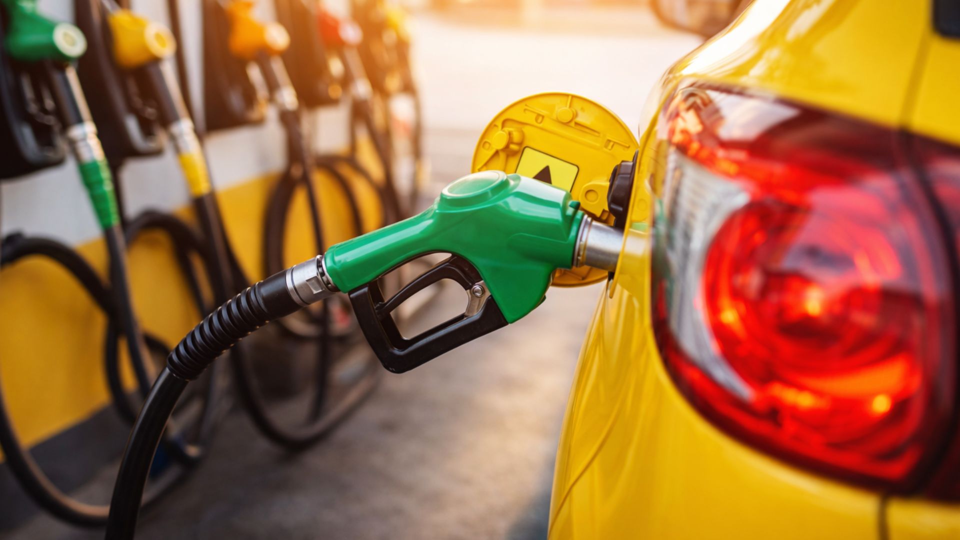 Carro sendo abastecido em posto de combustível com destaque para bomba de gasolina, representando o aumento da mistura de etanol no Brasil.