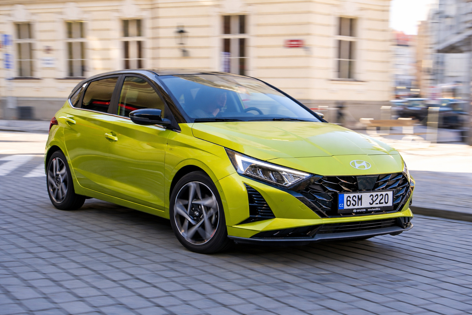 Hyundai hatch verde em movimento em rua urbana europeia, representando modelo compacto que pode inspirar novo SUV maior que o HB20 no Brasil