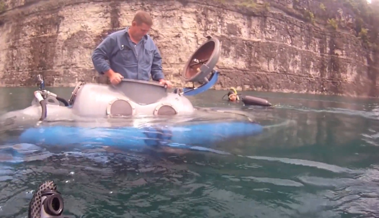 submarino feito com tanque de propano mergulhando em lago com agricultores ao redor