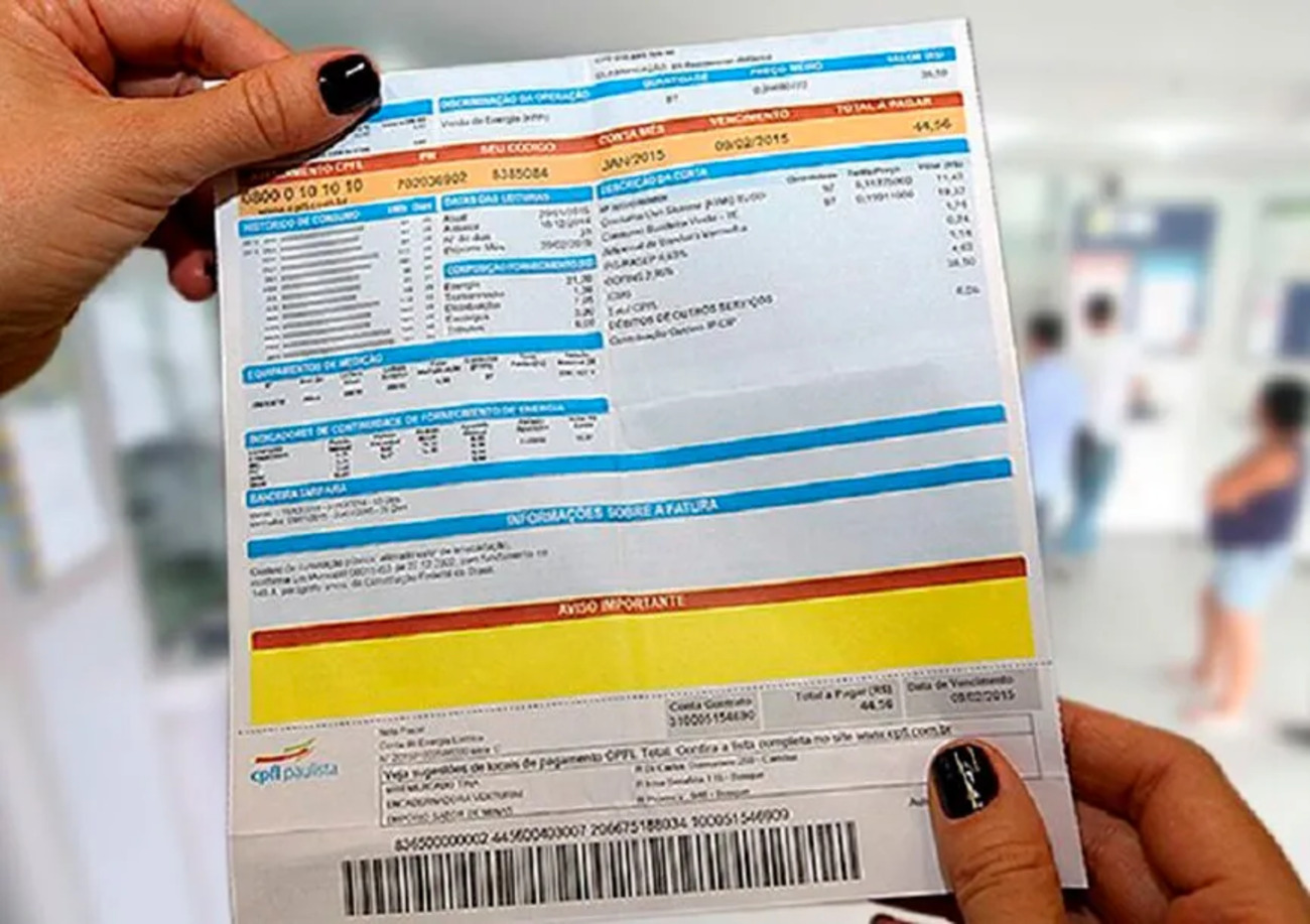Pessoa segurando uma conta de energia elétrica com detalhes de consumo e valores a pagar.
