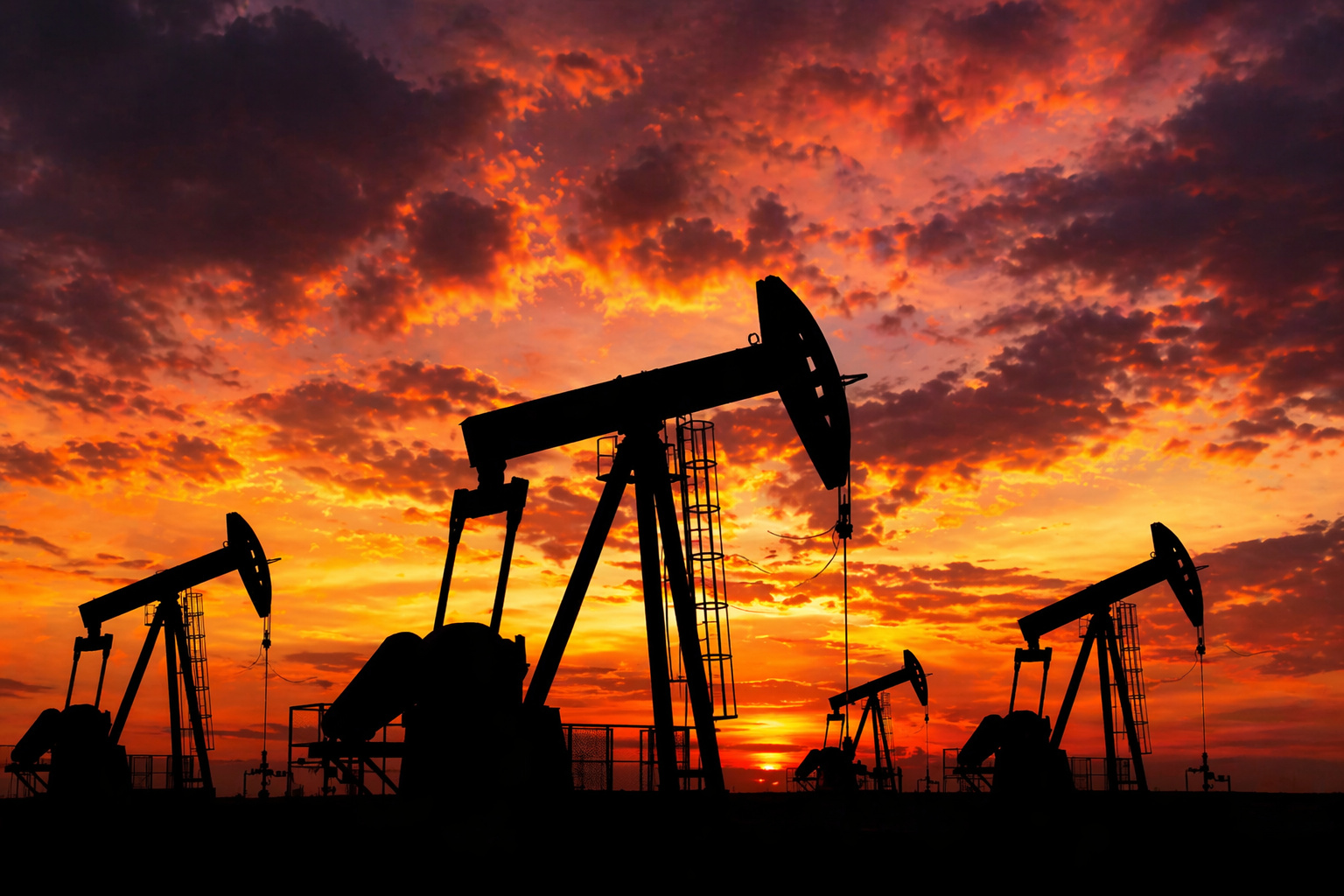 Bombas de extração de petróleo em silhueta ao pôr do sol em campo petrolífero