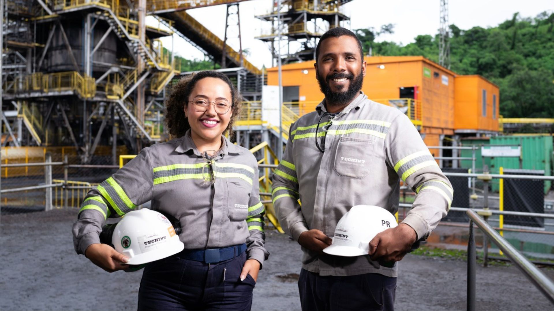 Profissionais da Techint E&C em ambiente industrial segurando capacetes de segurança durante atividade em obra, representando oportunidades do Programa Global de Trainees no Brasil