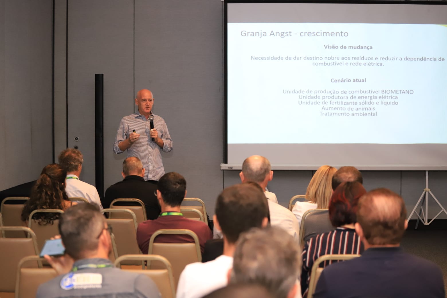 Palestrante apresentando projeto sobre biogás para público em conferência.