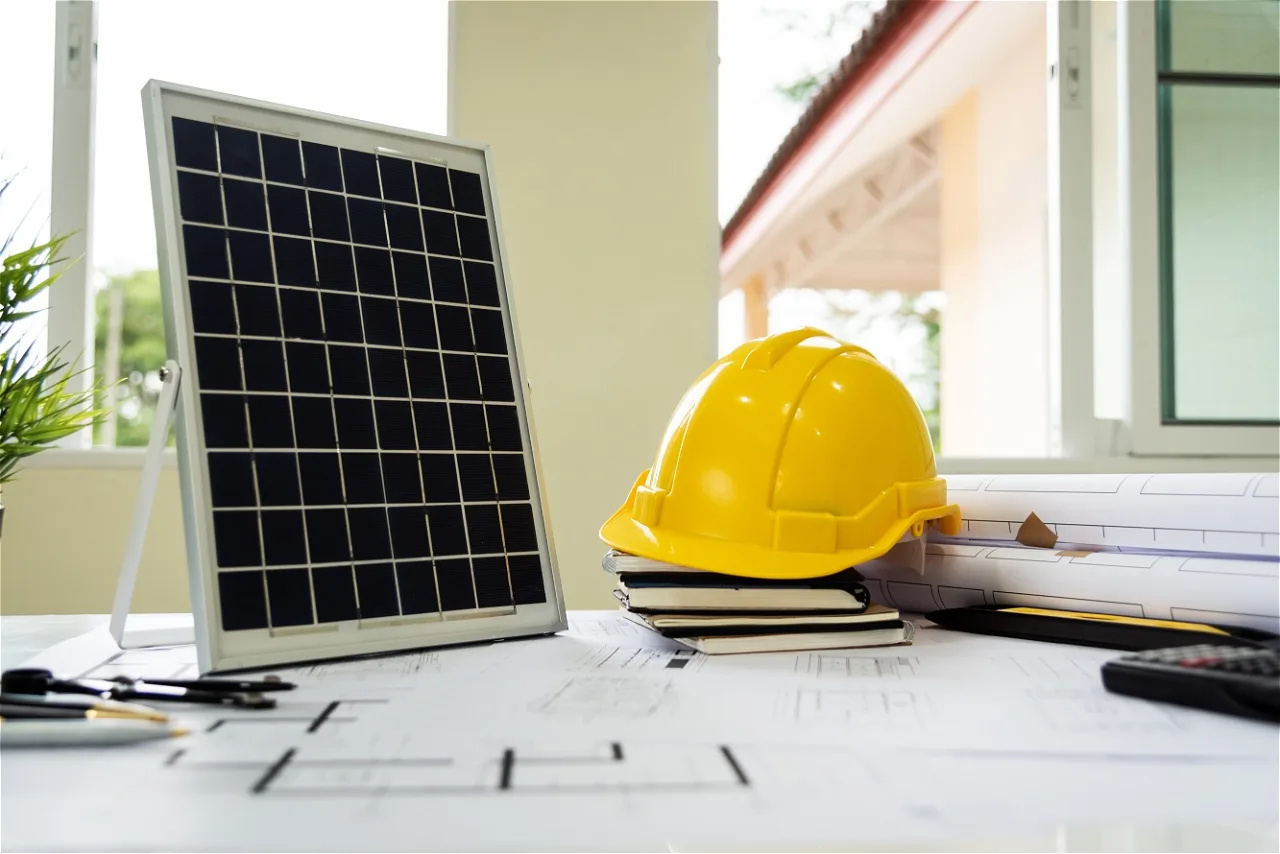 Painel solar em mesa com capacete de segurança e projetos de engenharia