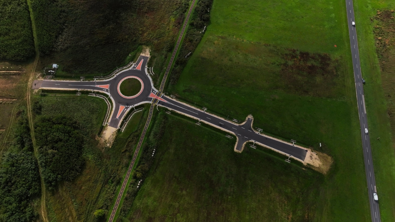 Vista aérea de una rotatória isolada no meio de campos verdes na Hungria, construída para um projeto logístico que ainda não foi concluído