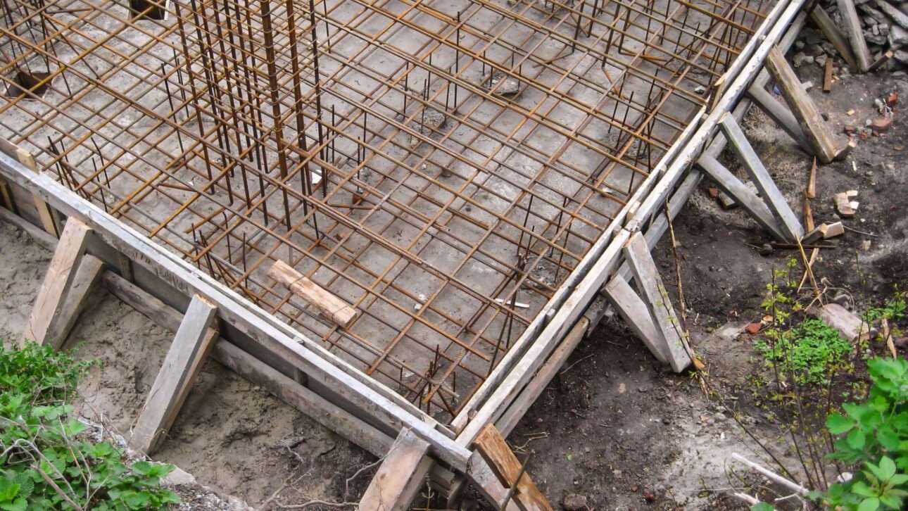 Armadura de aço e formas para radier mostram etapa essencial antes da concretagem da fundação rasa residencial.