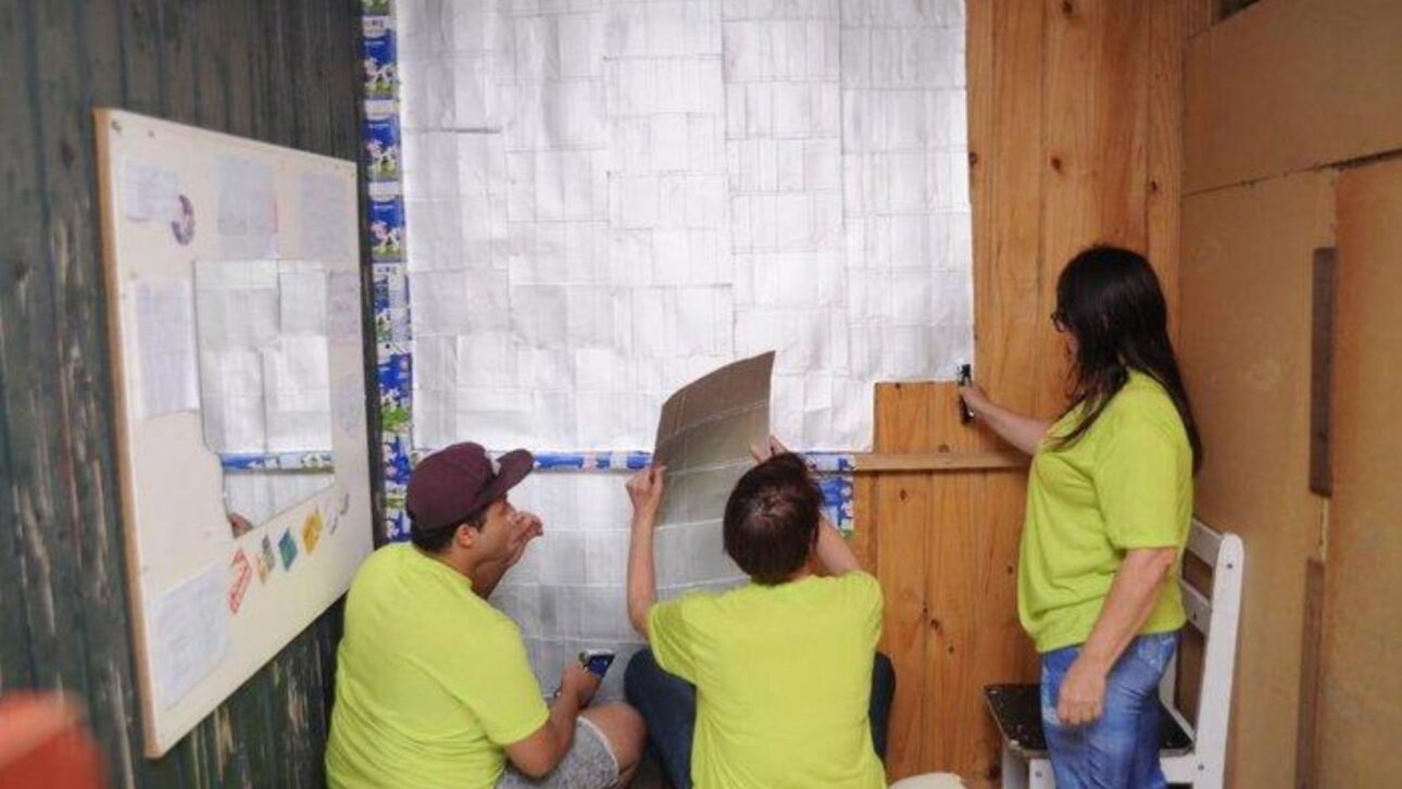 Projeto usa caixas de leite reutilizadas para revestir casas de madeira com frestas e proteger famílias em moradias precárias no Brasil.
