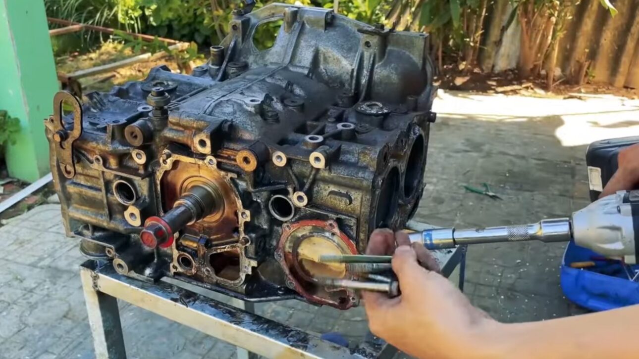 Homem adapta motor automotivo em iate artesanal com sistema náutico funcional, refrigeração externa e casco reforçado.