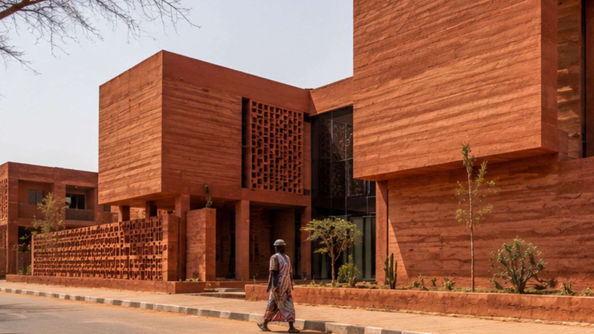 Material de terra volta à África com barro vermelho no Goethe-Institut, desafiando concreto cinza em cidades quentes e projetos modernos sustentáveis.