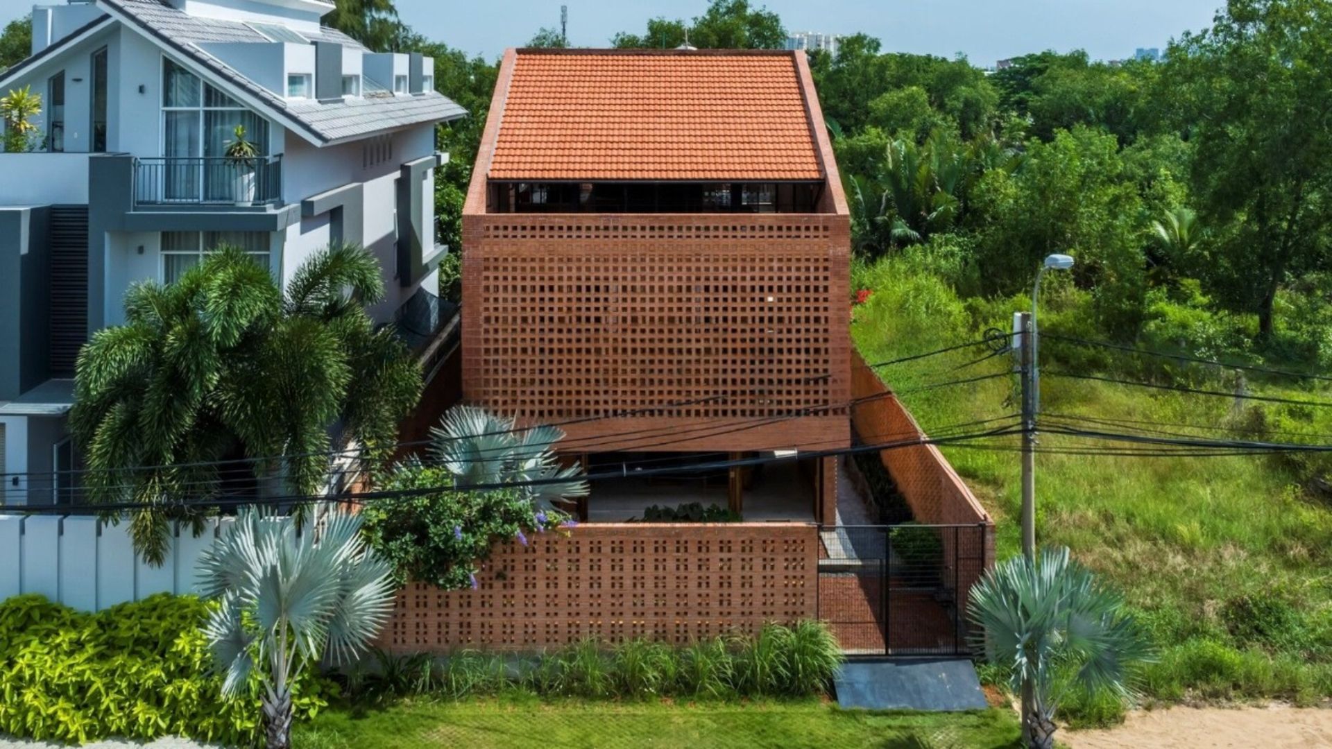 Casa Nhà Bè, no Vietnã, usa fachada de tijolos cerâmicos perfurados para filtrar luz e calor. Projeto reúne quatro irmãs e a mãe em arquitetura que respira pelas paredes.