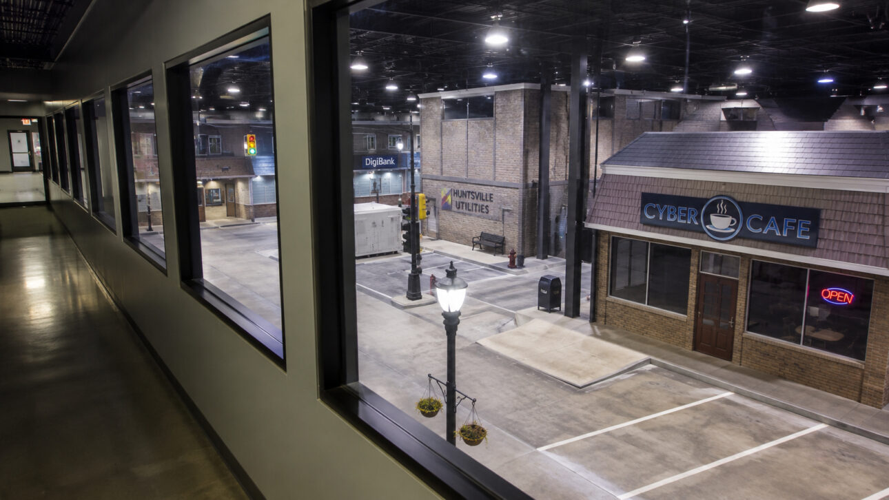 Ambiente urbano cenográfico dentro da instalação Kinetic Cyber Range, com prédios comerciais, ruas simuladas e estruturas utilizadas pelo FBI para treinamento contra crimes cibernéticos e ransomware.