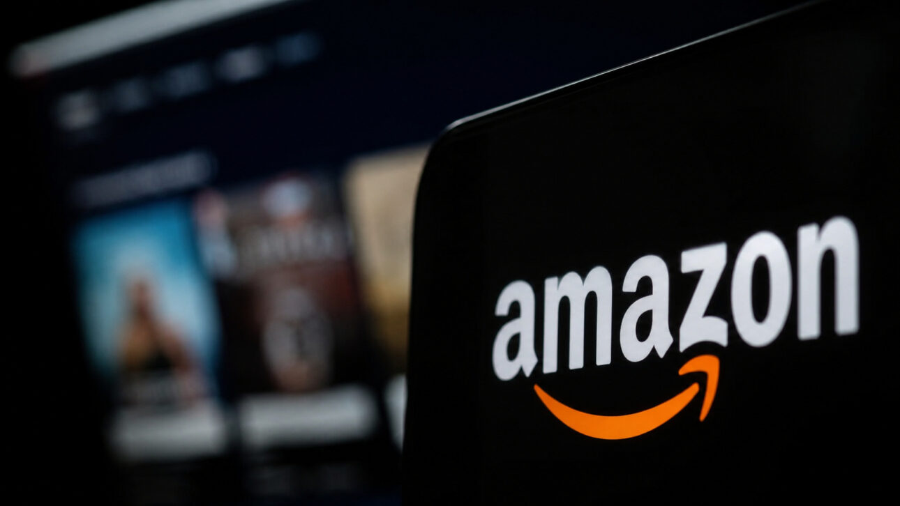 Logotipo de Amazon en pantalla oscura con interfaz digital desenfocada al fondo, ilustrando artículo sobre computación cuántica comercial, IA y avance tecnológico de la empresa.
